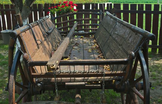 Old rustic vintage carriage in front of fence in backyard