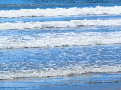 Small white waves, sparkling and bright, on sunny days, in the blue sea.