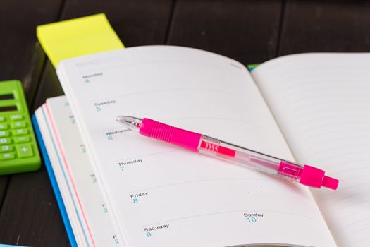 Open diary, pen on a black wooden background