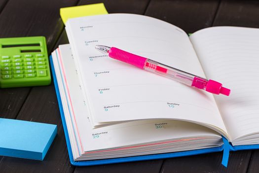 Open diary, pen on a black wooden background