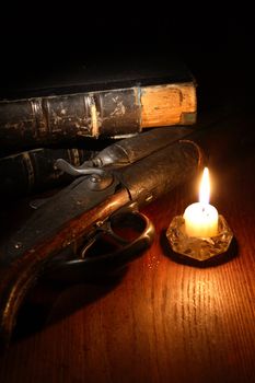 Vintage still life with hunting shotgun near candle and old books