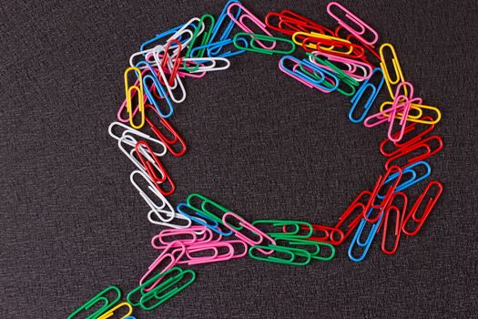Colored paper clips on the black background