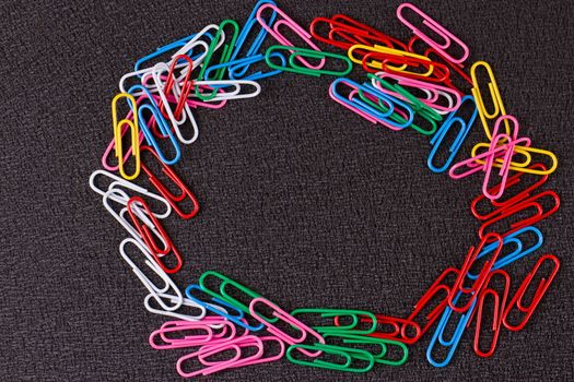 Colored paper clips on the black background