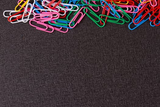 Colored paper clips on the black background