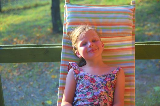 Small girl is taking a sunbath in the garden. Dreamy and romantic image. Summer and happy childhood concept.