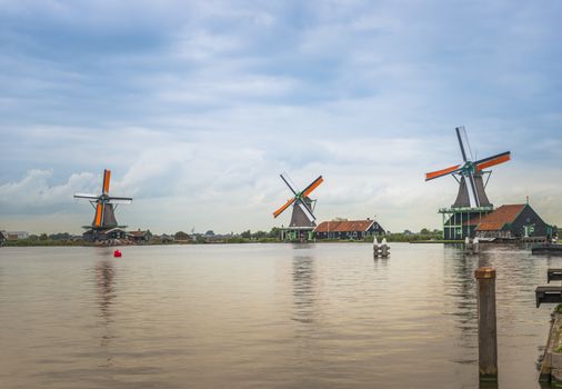 Authentic Zaandam mills on the water channel in Zaanstad village. Zaanse Schans Windmills and famous Netherlands canals, Europe.
