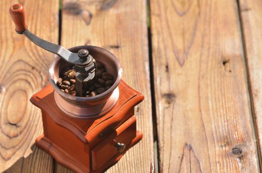 Coffee grinder with coffee beans on wooden boards