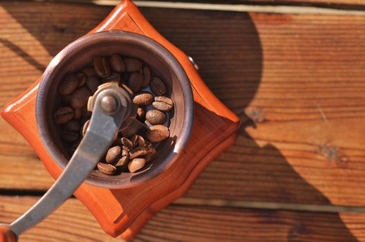 Manual coffee grinder with coffee beans on wooden background