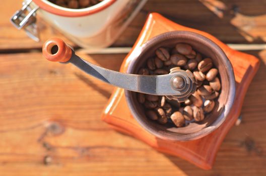 Manual coffee grinder with coffee beans on a wooden background closeup