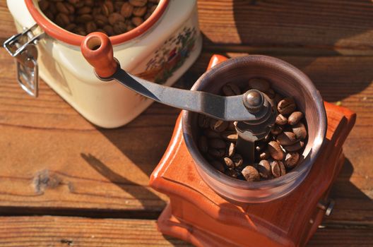 Handmade coffee mill and a jar of coffee beans on a wooden background close up