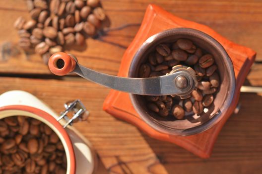 Handmade coffee grinder with large coffee beans, vase with grains, coffee beans on wooden boards