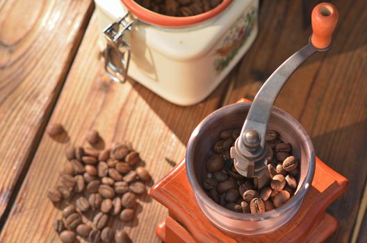 Handmade coffee grinder with large coffee beans, vase with grains, coffee beans on dark wooden boards