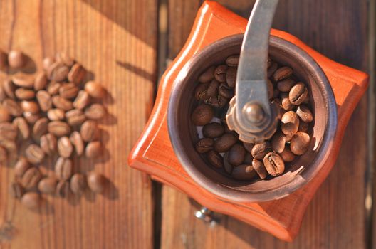 Handmade coffee grinder with large coffee beans, coffee beans on dark wooden boards