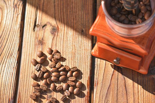 Manual coffee grinder with good roasted coffee beans, coffee beans on dark wooden boards