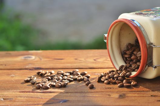 From the beautiful clay cans on the wooden boards poured roasted coffee beans, against the background of greenery and water