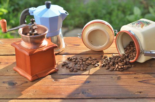 Clay pot of which grains are poured, handmade coffee grinder and coffee machine on wooden boards