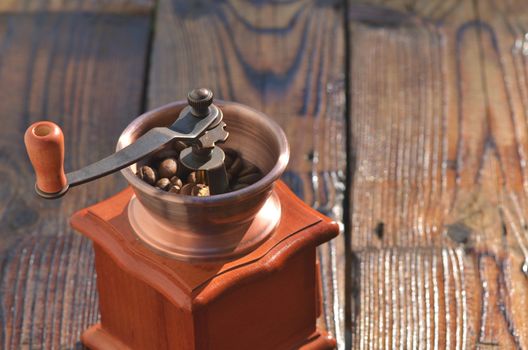 Coffee grinder with coffee beans on wooden boards, texture, background