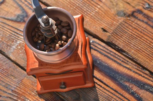 Manual horizontal grinder with roasted coffee beans on wooden boards