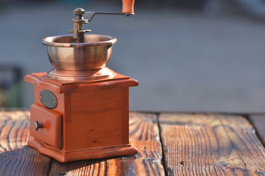 Manual horizontal coffee grinder on wooden boards, against the background of water