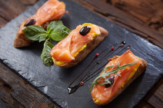 The tasty bruschetta with salmon on black stone