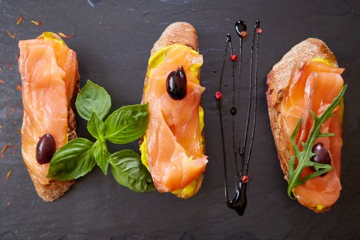 The tasty bruschetta with salmon on black stone