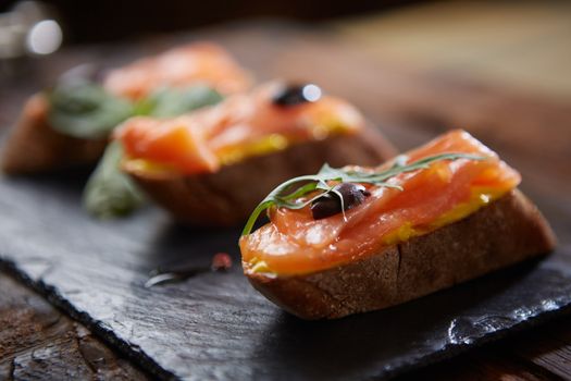 The tasty bruschetta with salmon on black stone