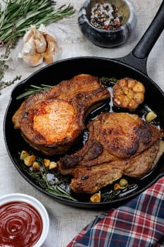 Roasted pork loin steak in a frying pan with tomato sauce and spices