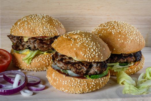 Three fresh burger lay on the board. Homemade fast food more tasty and healthy.