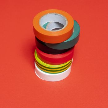 some rolls of colored insulating tape on a red surface