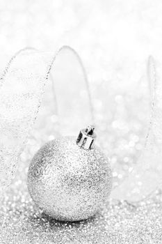 Christmas decorative ball and ribbon on silver glitter background