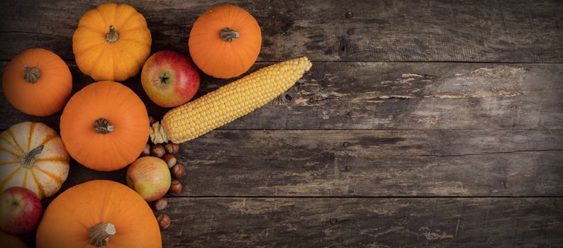 Autumn harvest still life with pumpkins, apples, hazelnut, corn, on wooden background, top view with copy space