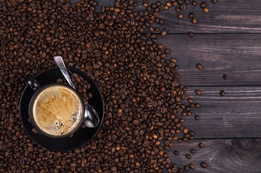 Coffee background, top view with copy space. Coffee cup and coffee beans on black wooden background