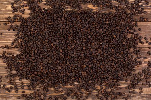 Coffee beans on brown wooden background, coffee texture, top view, copy space