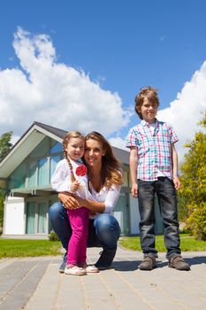 Portrait of happy smiling family of mother and children near their house