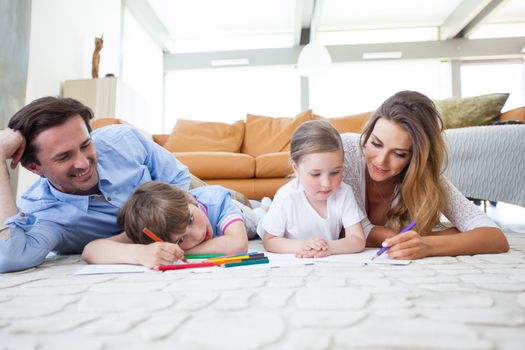 Charming family with children drawing together on the floor in a living room