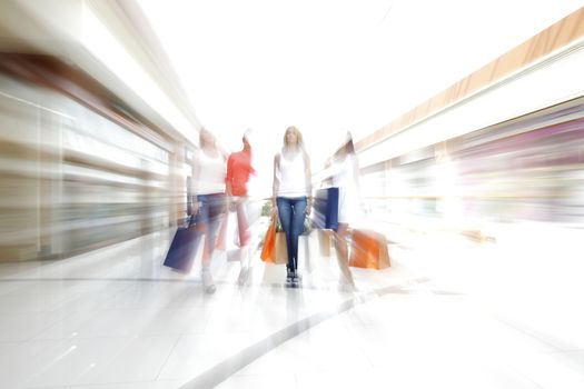 Women walking fast in shopping mall with bags