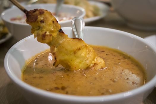 Malaysian chicken satay dip into delicious peanut sauce, one of famous local dishes.