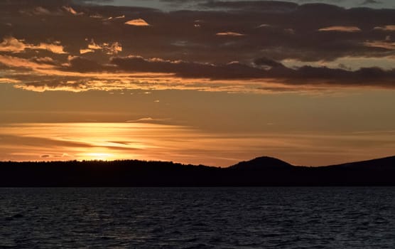 Golden sun sinks over the lake in the evening, golden water, South Ural lake Uvildy