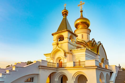 Beautiful view during sunset at the temple of St. Seraphim of Sarov in the city of Khabarovsk. A beautiful green lawn in the foreground. Religious architecture, buildings and traditions. Russia.