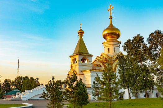 Beautiful view during sunset at the temple of St. Seraphim of Sarov in the city of Khabarovsk. A beautiful green lawn in the foreground. Religious architecture, buildings and traditions. Russia.