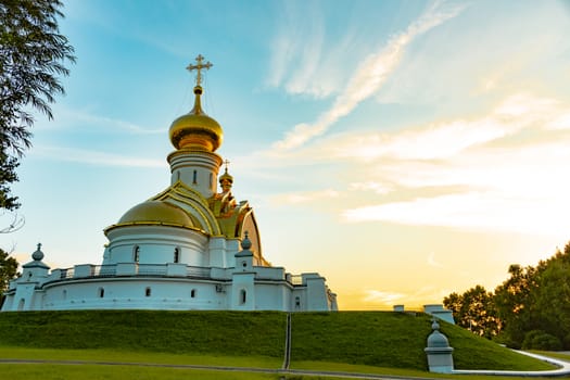 Beautiful view during sunset at the temple of St. Seraphim of Sarov in the city of Khabarovsk. A beautiful green lawn in the foreground. Religious architecture, buildings and traditions. Russia.