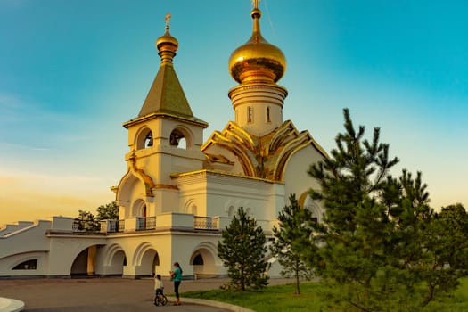 Beautiful view during sunset at the temple of St. Seraphim of Sarov in the city of Khabarovsk. A beautiful green lawn in the foreground. Religious architecture, buildings and traditions. Russia.