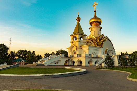 Beautiful view during sunset at the temple of St. Seraphim of Sarov in the city of Khabarovsk. A beautiful green lawn in the foreground. Religious architecture, buildings and traditions. Russia.