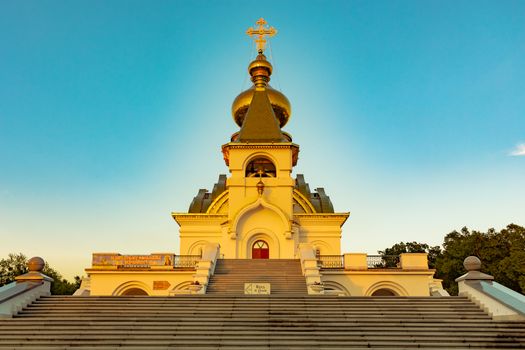 Beautiful view during sunset at the temple of St. Seraphim of Sarov in the city of Khabarovsk. A beautiful green lawn in the foreground. Religious architecture, buildings and traditions. Russia.