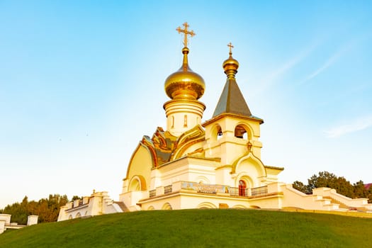 Beautiful view during sunset at the temple of St. Seraphim of Sarov in the city of Khabarovsk. A beautiful green lawn in the foreground. Religious architecture, buildings and traditions. Russia.