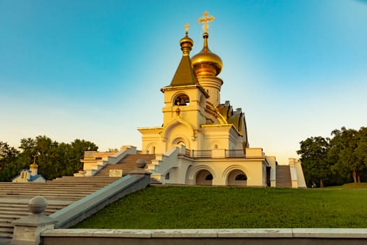 Beautiful view during sunset at the temple of St. Seraphim of Sarov in the city of Khabarovsk. A beautiful green lawn in the foreground. Religious architecture, buildings and traditions. Russia.