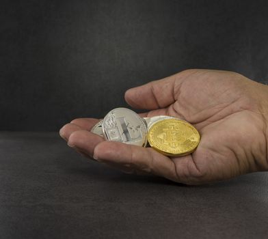 hand with bitcoin litecoin and other virtual coins with black background