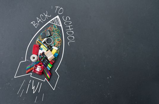 Back to school sketch of a rocket icon with stationery accessories on a chalkboard