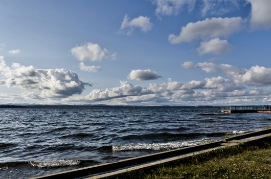 view of the lake with cumulonimbus clouds above it in windy weather