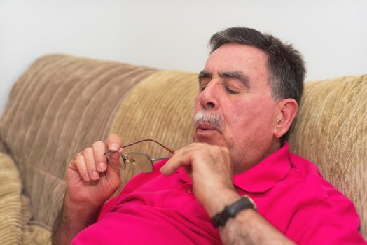 Senior man cleaning his glasses